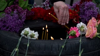 Eine Frau legt eine Kerze im Gedenken an die Opfer von Odessa nieder.
