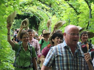 Die Wandergruppe durchschreitet einen begrünten Torbogen in heiterer Stimmung.
