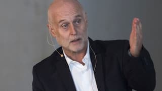 Ein Mann in Schale hält vor einer grauen Wand eine Rede. Ein Mann in Schale hält vor einer grauen Wand eine Rede.