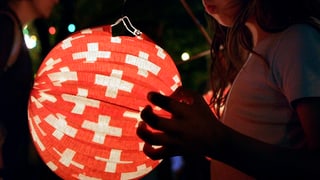 Kind hält Lampion mit Schweizer Kreuzen drauf