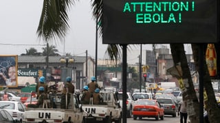 Autos fahren an einem Ebola-Warnschild vorbei.