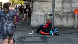 Ein Mann sitzt am Boden und bettelt um Geld.