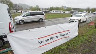 Transparent mit der Aufschrift "Keine Plätze! Wohin?" im Hintergrund Autos und Wohnwagen