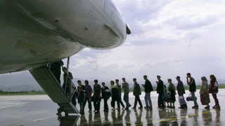 Eine Gruppe steht Schlange, um in ein Flugzeug zu steigen. 