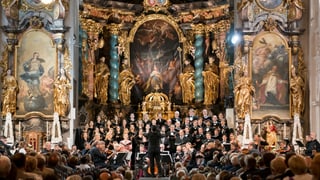 Ein Orchester spielt vor Publikum in einer prunkvollen Kirche.