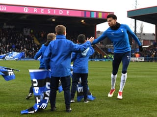 Dele Alli klatscht mit Ballbuben auf dem Rasen ab