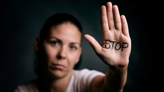 Eine Frau zeigt ihre Handfläche, auf der Stop steht.
