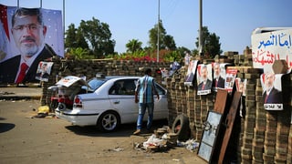 Barrikade mit Mursi-Postern. Daneben ein Auto. 