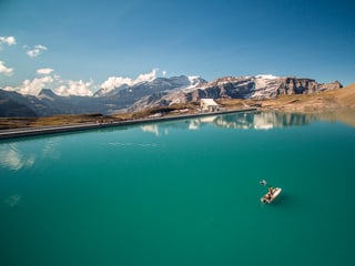 Boot auf See, im Hintergrund ist die Staumauer und Berge erkennbar.
