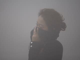Frau im Smog schützt sich mit ihrer Kleidung Frau im Smog schützt sich mit ihrer Kleidung