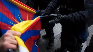 Polizist senkt eine Tibetfahne an einem Protest in Bern am 15. Januar 2017