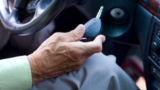 Greise Hand hält Autoschlüssel Greise Hand hält Autoschlüssel