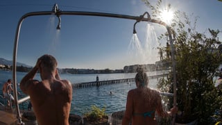 Zwei Personen duschen in Badehose bei strahlendem Sonnenschein Zwei Personen duschen in Badehose bei strahlendem Sonnenschein