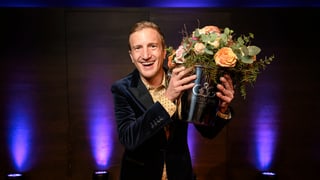 Mann in blauem Jackett mit Blumenstrauss in der linken Hand