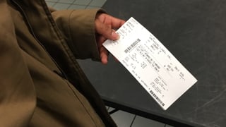 Eine Person hält ein Ticket in den Händen.