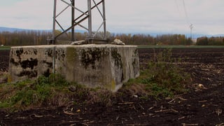 Abgesunkener Boden um das Fundament eines Strommasts