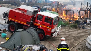 Feuerwehrwagen neben brennendem Gerüst