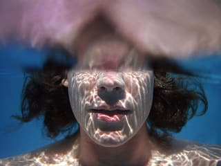 Eine Frau hält die untere Hälfte des Kopfes unter Wasser.