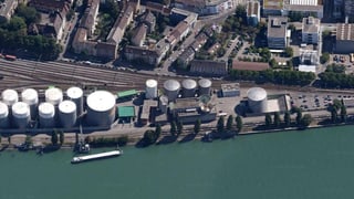 Die Tanklager von Esso von oben herab fotografiert, im Vordergrund der Rhein mit Schiff, dahinter Bahngleise und Häuser des Klybeckquartiers.