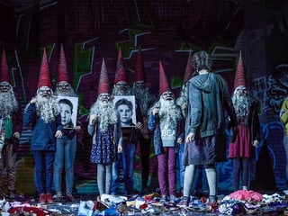 Zwerge in blauen Kleidern und mit lila, spitzigen Hüten. Davor steht Gretel. Zwerge in blauen Kleidern und mit lila, spitzigen Hüten. Davor steht Gretel.