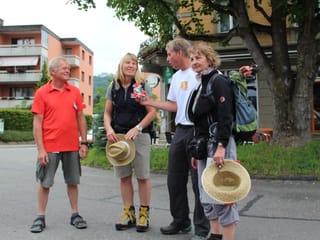 Gruppenbild mit zwei Wanderinnen, einem Wanderer und Reto Scherrer. Er hält ein kleines Präsent in Händen.