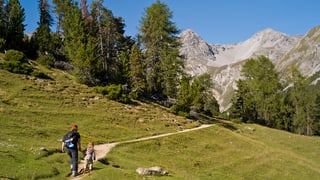 Frau läuft mit Tocher auf einem Wanderweg