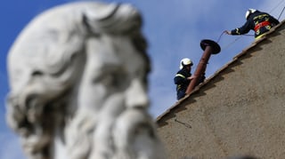 Arbeiter auf dem Dach. Davor Kopf einer Statue.