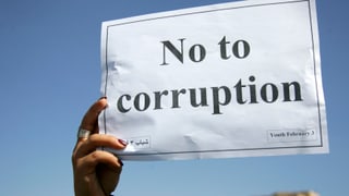 Eine weibliche Hand hält ein Papier, darauf steht No to corruption.