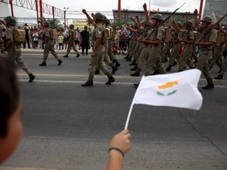 Ein Junge schwenkt eine zypriotische Fahne an einer Militärparade.
