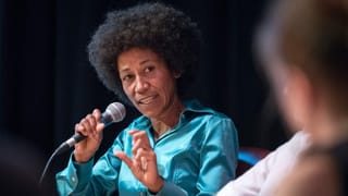 eine Frau redet an einem Podium mit einem Mikrofon eine Frau redet an einem Podium mit einem Mikrofon