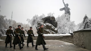 Sicherheitskräfte marschieren an einer Statue in Wolgograd vorbei. Sie tragen lange Mäntel und Stiefel. Sicherheitskräfte marschieren an einer Statue in Wolgograd vorbei. Sie tragen lange Mäntel und Stiefel.