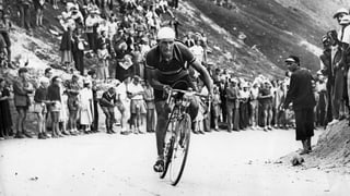 Schwarzweissbild: Bartali auf dem Rennrad auf einer Bergstrasse. Am Strassenrande zahlreiche Zuschauer.