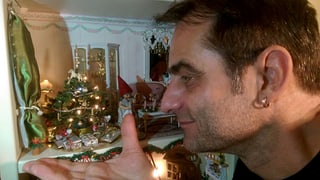 Thomy Scherrer hält seine Hand unter einen Miniatur-Weihnachtsbaum. 
