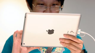 Eine Asiatin hält ein iPad vor sich.