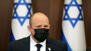 Mann mit Maske vor israelischen Fahnen.