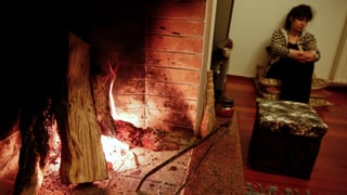 Eine Frau sitzt vor dem Kamin. Eine Frau sitzt vor dem Kamin.