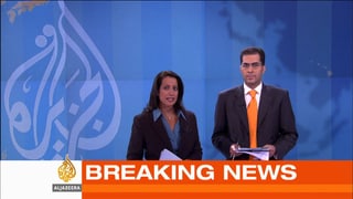Eine Frau und ein Mann im Nachrichtenstudio davor einen Breaking-News-Einblender.