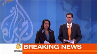Eine Frau und ein Mann im Nachrichtenstudio davor einen Breaking-News-Einblender. Eine Frau und ein Mann im Nachrichtenstudio davor einen Breaking-News-Einblender.