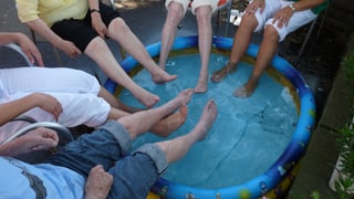 Pflegende und ältere Menschen kühlen ihre Füsse in einem Kinderplantschbecken.