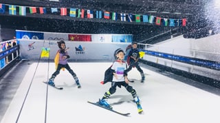Chinesische Kinder fahren in einer Indoor-Skihalle Chinesische Kinder fahren in einer Indoor-Skihalle