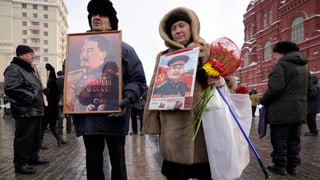 Zwei alte Russen tragen Bilder von Stalin durch die Strassen von Moskau