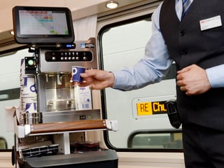 Minibar-Steward lässt an der modernen Kaffeemaschine einen Becher Kaffee heraus