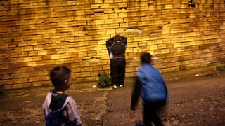 Drei spielende Kinder vor einer glänzenden Wand.