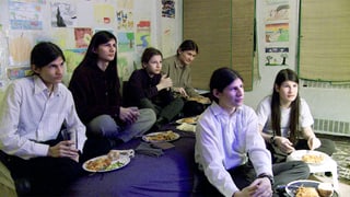 Sechs Jugendliche, die Fernseh schauen und gleichzeitig essen.