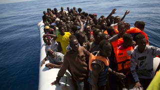 Dutzende afrikanische Migranten in einem Gummiboot auf em Meer.