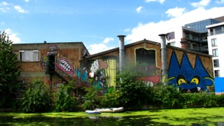 Mit Graffitti beschmiertes, verfallendes Industriegebäude am Fluss.