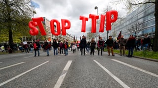 Menschen auf einer Strasse, sie halten grosse rote Buchstaben in die Höhe, welche «Stopp TTIP» bilden.
