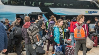 Jungedliche mit Gepärck vor einem Bus