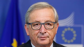 Jean-Claude Junkcer bei einer Pressekonferenz. Im Hintergrund die EU-Symbole.