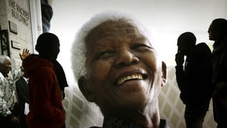 Ein grosses Bild vom lachenden Nelson Mandela, begutachtet von Kunstinteressierten.